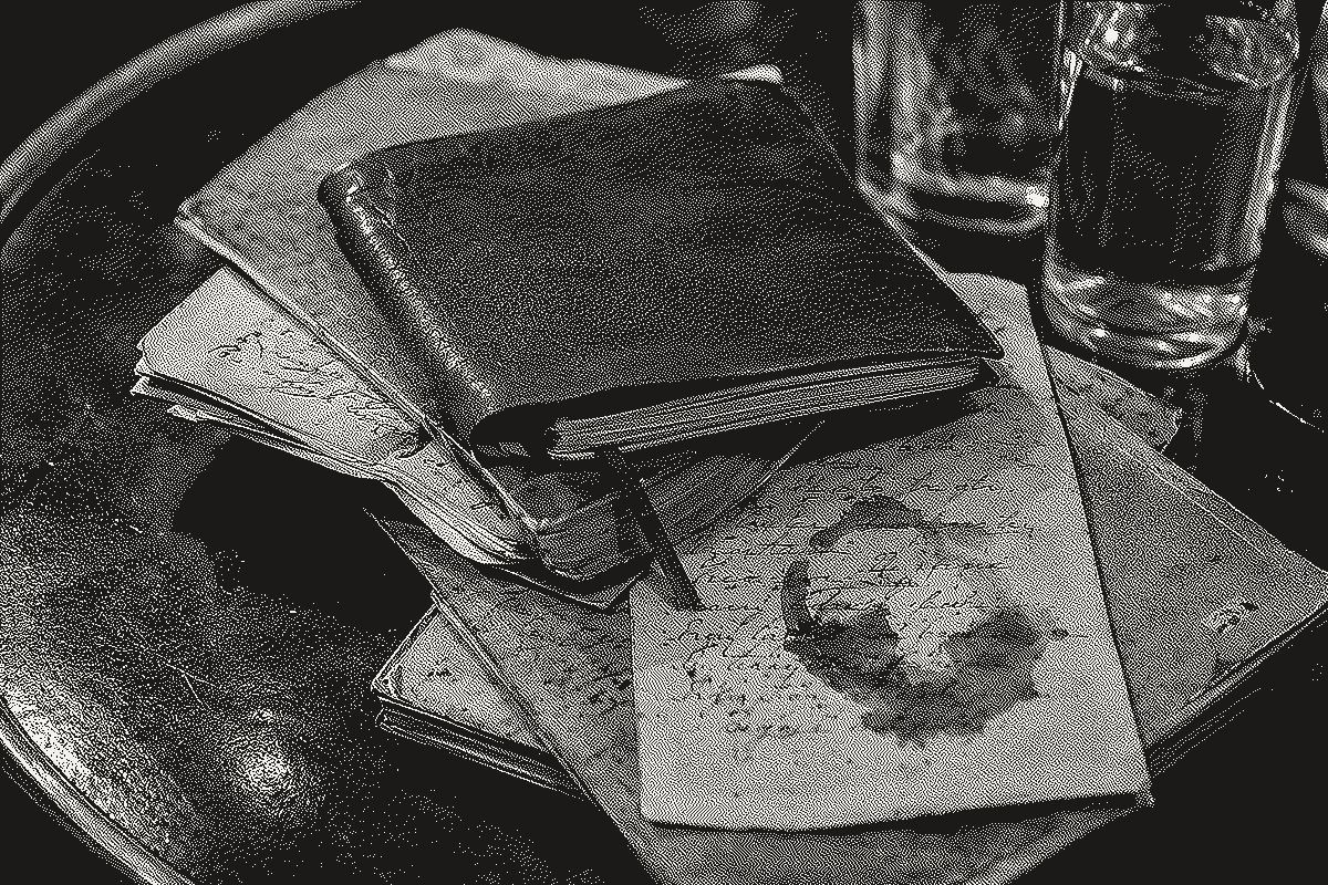 A stack of aged leather notebooks and loose, handwritten letters, one stained with wine